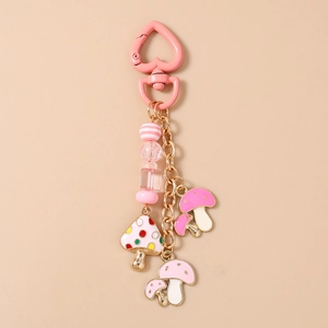 Détail d'un fermoir coeur en métal rose avec chaîne perlée et breloques champignon