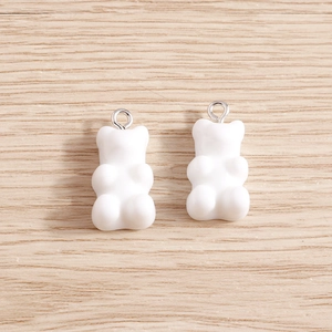 Set of two white resin gummy bear charms with silver metal rings on a wood background