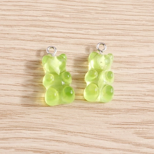 Light green translucent gummy bear resin charms with silver rings on wood surface
