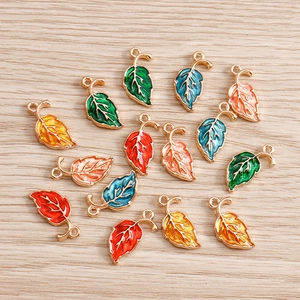 Detailed close-up of colorful maple leaf enamel charms with gold frames for DIY jewelry