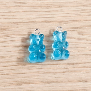 Close-up of two blue resin gummy bear charms with silver metal rings for DIY jewelry
