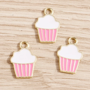 Détail de trois pendentifs cupcakes roses en émail blanc et bordure en alliage doré