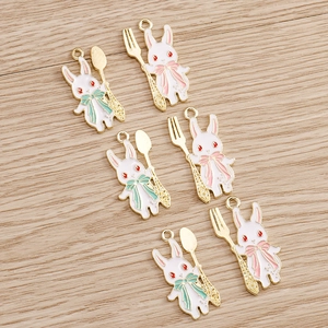 Detail von weißen Emaille-Hasenanhängern mit goldenen Löffeln und Gabeln für DIY-Schmuck