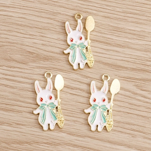 Detailansicht von drei weißen Kaninchen-Emaille-Anhängern mit goldenen Löffeln für DIY-Schmuck