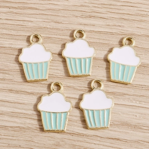 Gros plan de cinq pendentifs cupcakes en émail vert menthe sur fond de bois clair