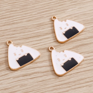 Macro shot of three triangular onigiri enamel charms with gold edges on wood background