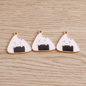 Macro detail of rice ball enamel charms with cute expressions and golden metal loops
