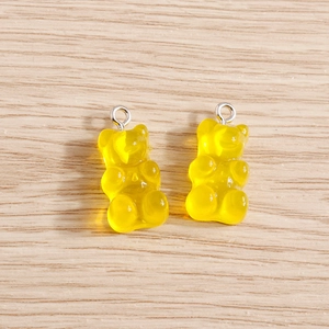 Close-up of translucent yellow resin gummy bear charms with silver metal rings for DIY jewelry