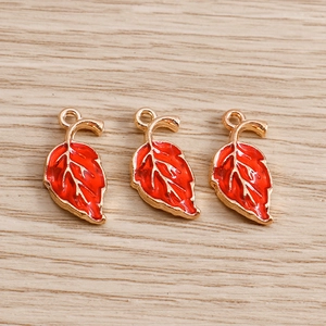 Detailed close-up of three red enamel maple leaf charms with golden metal edges