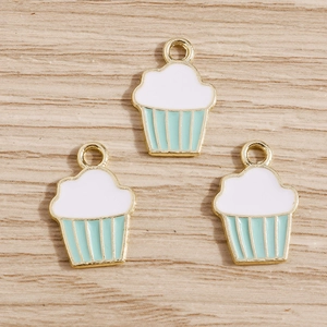 Vue détaillée de trois breloques cupcakes en émail sur un fond en bois naturel rustique