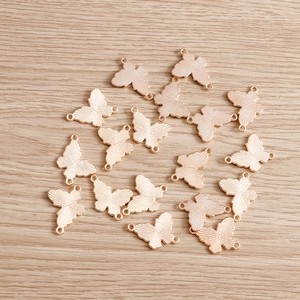 Rose gold alloy butterfly charms with dual rings on a natural wood background