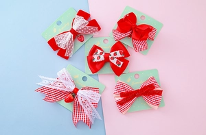 Détail de 5 barrettes à nœuds rouge et blanc avec dentelle et breloque fraise