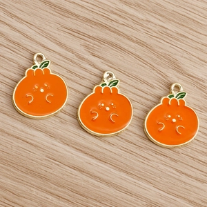 Macro shot of three cute enamel orange pendants with smiling faces on wooden background