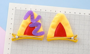Vue détaillée des barrettes oreilles de chat en peluche jaune sur grille de mesure