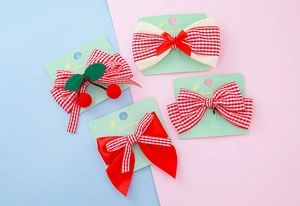 Détail de nœuds à carreaux rouges et barrettes cerise sur carte bijoux