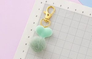 Dettaglio portachiavi a cuore in peluche verde menta con chiusura dorata e velluto