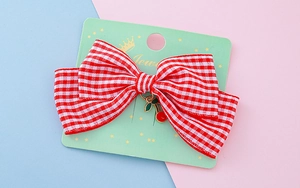 Détail d'un nœud papillon en tissu à carreaux rouges avec pendentif cerise