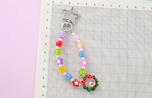Detailed view of a Christmas beaded keychain with snowman charm on a measuring grid board