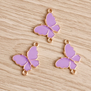 Detailed macro view of purple enamel butterfly connectors with gold metal edges for DIY jewelry