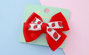 Vue détaillée d'une pince à cheveux à nœud rouge mignon avec motifs fraises sur carte