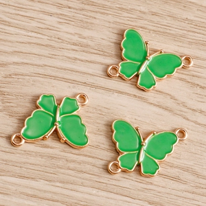 Detailed view of green enamel butterfly connectors with gold metal edges for DIY jewelry