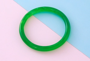 Gros plan d'un bracelet jonc rond vert émeraude lisse avec des textures marbrées