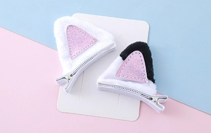 Détail de barrettes oreilles de chat en peluche avec paillettes roses sur carte