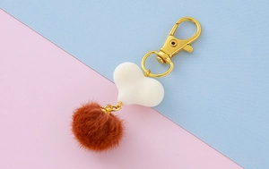 Dettaglio di un ciondolo a cuore in peluche con chiusura dorata e pendente a cuore bianco