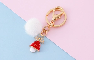 Détail d'un porte-clés de Noël à pompon avec cloche de renne rouge et métal doré brillant