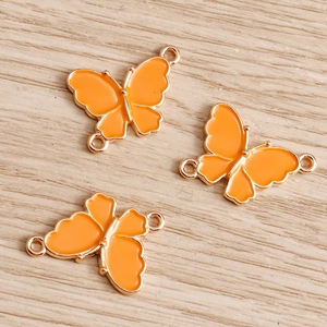 Detail of orange enamel butterfly charms with rose gold edges and double connectors