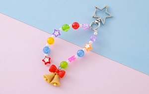 Macro detail of colorful beaded keychain with red bow and yellow bells on star clip