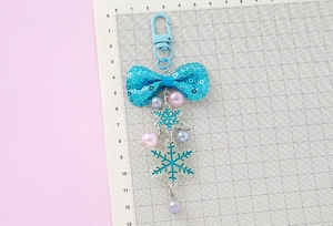 Size display of a blue sequin bow snowflake keychain with colorful pearls, 13cm length