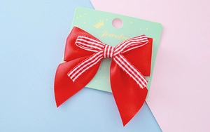 Détail d'un nœud papillon en satin rouge avec ruban rayé sur carte de bijouterie