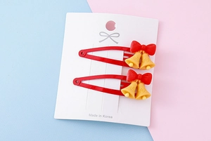 Detail of red bow and yellow bell resin charms on metal BB hair clips for kids