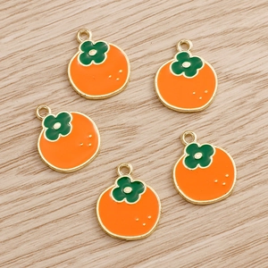 Close-up of five orange persimmon alloy charms for DIY jewelry making on wood background