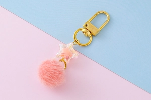 Detail of pink star keychain with fluffy faux fur ball and golden metal D-ring buckle