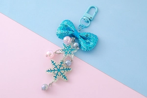 Close-up of glitter bow keychain with snowflake pendants and pastel gradient beads