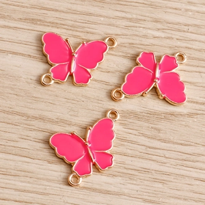 Detailed view of rose pink enamel butterfly charms with gold alloy edges for DIY jewelry