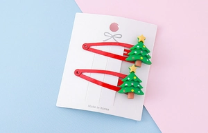 Detail of red Christmas tree hair clips with yellow stars on a white card display
