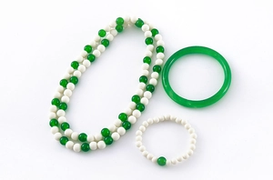 Gros plan d'un ensemble collier, bracelet et bague en perles vert et blanc style jade poli