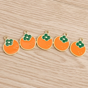 Detail view of five orange persimmon alloy pendants with green calyx for DIY jewelry