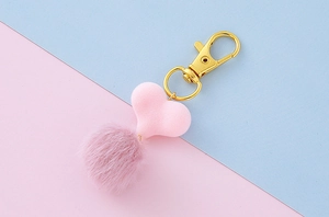 Portachiavi a cuore in ecopelliccia rosa con gancio in metallo dorato su sfondo pastello