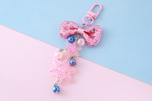 Pink sequin bow keychain with iridescent beads and transparent snowflake charm detail
