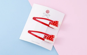 Detail of red Christmas hair clips featuring cute Santa hats with yellow star ornaments