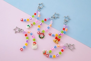 Set of 5 Christmas beaded keychains featuring Santa, snowman, and bell charms on pink background