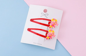 Detail of red Christmas candy cane hair clips with pink bows on a display card