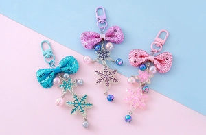Close-up of glitter bow and acrylic snowflake keychain charms in blue, purple, and pink
