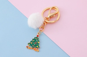 Détail du pendentif sapin de Noël en émail et pompon blanc sur porte-clés doré