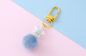 Close-up of star keychain with blue faux fur pompom and golden lobster clasp
