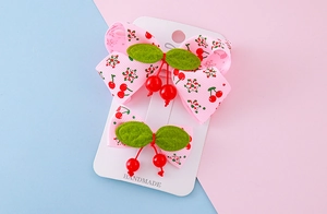 Close-up of pink cherry bow hair clips for girls on a white handmade display card